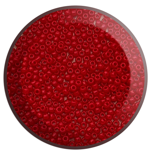 A close-up image of small, pepper red opaque transparent Toho round seed beads used for beading and jewelry making.
