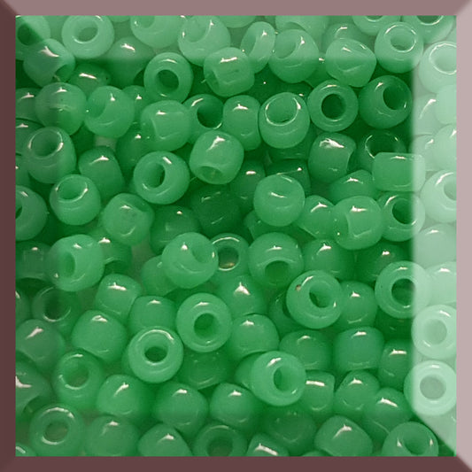 A collection of jade green, round Toho seed beads arranged in a pattern.