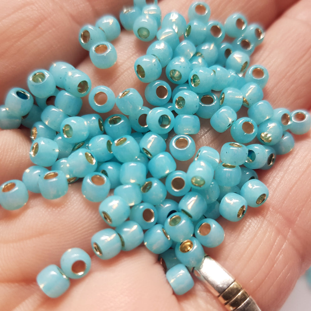 close up milky aqua beads on a hand.