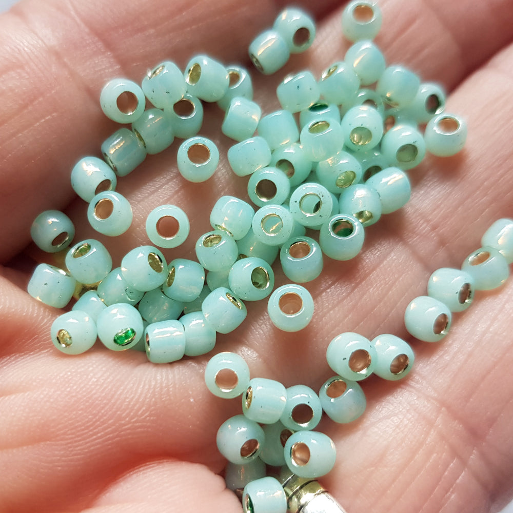 close up milky peridot beads on a hand.