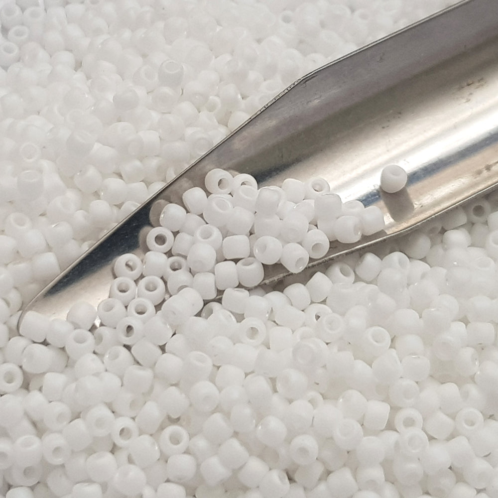 close up white frosted beads with a beading scoop
