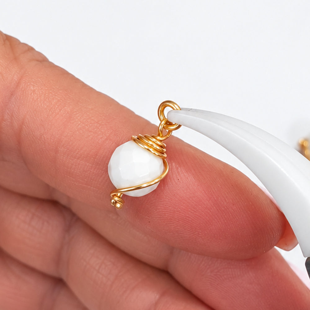 Five handmade 8 mm white howlite bead drop dangles with gold-coloured wire and open jump rings on a white background