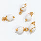 Cluster of handmade white howlite bead drop dangles hanging from a gold-coloured hoop and held in hand