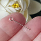 Eye Pins 20mm - 24 gauge (0.5mm) Sterling Silver (10pc Pack) | between fingers blurred flower background.