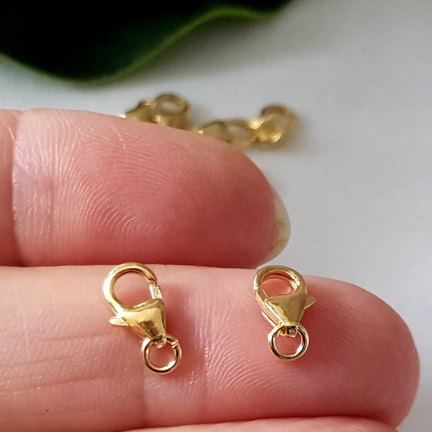 2 gold plated lobster claw clasps on a finger
