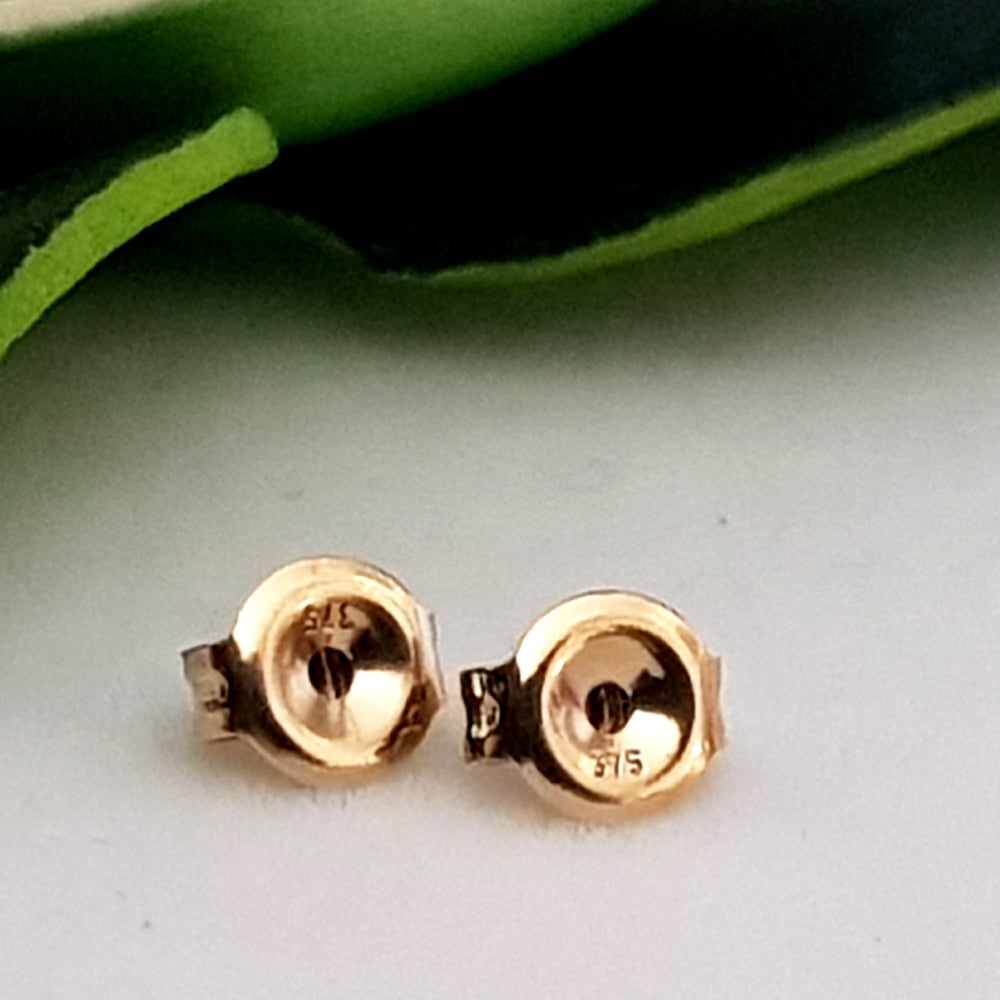A pair of 9ct yellow gold butterfly ear backs for earrings, displayed against a green leafy background.
