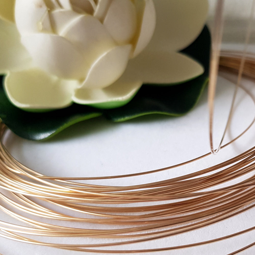 9ct Yellow Gold wire with a white flower in the background.