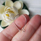 A single kidney hook on hand blurred flower background.