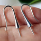 A close up of sterling silver hooks for half drilled pearls or gemstones, on a hand blurred background.