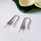 Side close up of a pair sterling hooks laying flat on white background 
