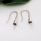A pair of sterling silver hooks laying flat on a white background.