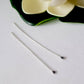 Argentium Long 60mm 2pcs Headpins Balled Flat a pair laying flat on a white background with a flower on top.