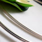 A close-up image of a sterling silver double half-round wire, showing its milled texture and metallic sheen.