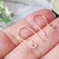 gold earring hooks on fingers blurred background