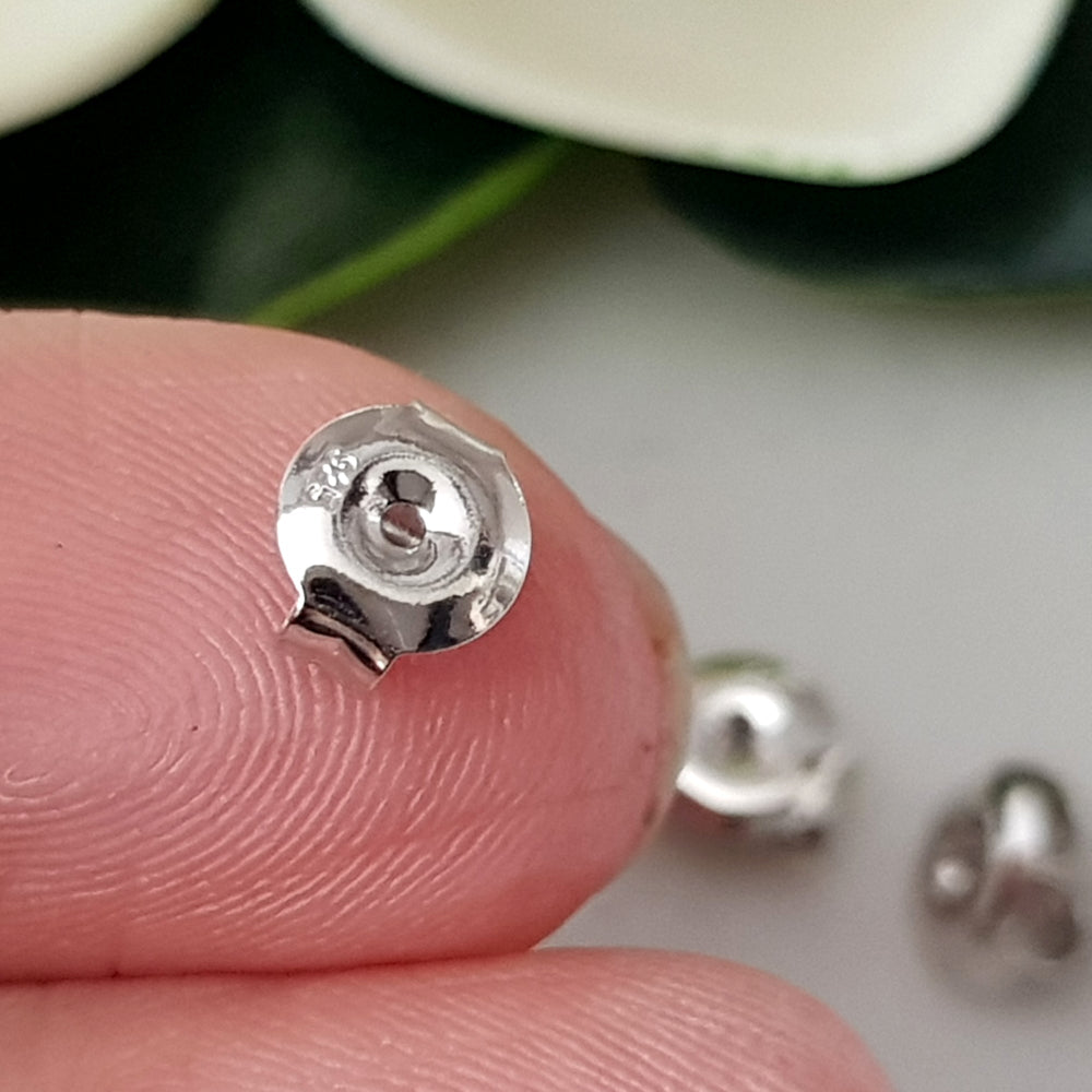 Close up on a finger sterling silver medium weight earring backs.