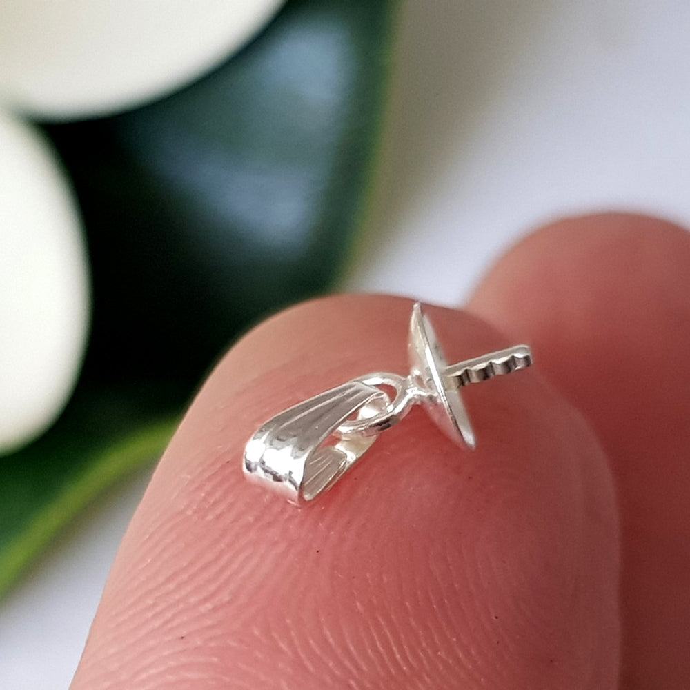 A sterling silver pendant drop with bail resting on a fingertip, designed for holding pearls or gemstones.