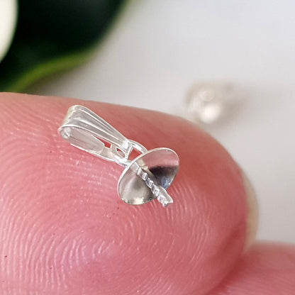 Sterling silver 925 Pendant Drop on a finger blurred background.
