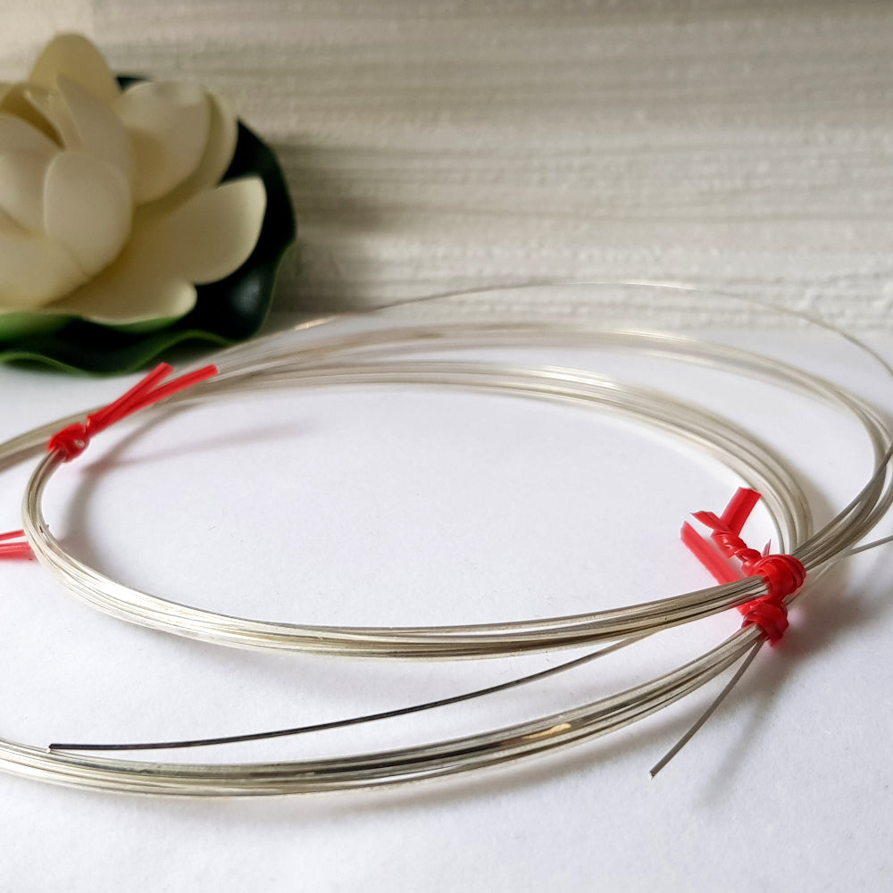 A coiled piece of sterling silver 925 square wire with red clips on the ends, labeled for jewellery making supply.