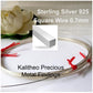 A spool of sterling silver square wire labeled for jewelry making, with a small white flower in the background.