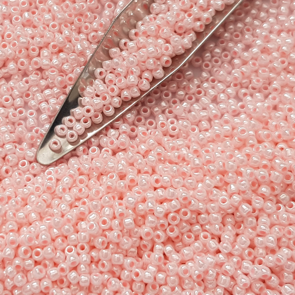 A round container filled with baby pink opaque luster Toho seed beads. 11/0 beading scoop