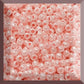 A round container filled with baby pink opaque luster Toho seed beads. 11/0 square window.