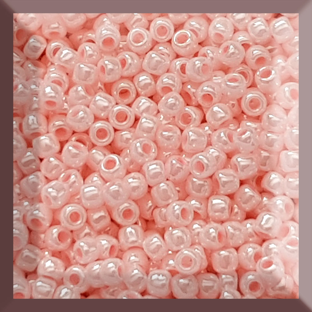 A round container filled with baby pink opaque luster Toho seed beads. 11/0 square window.
