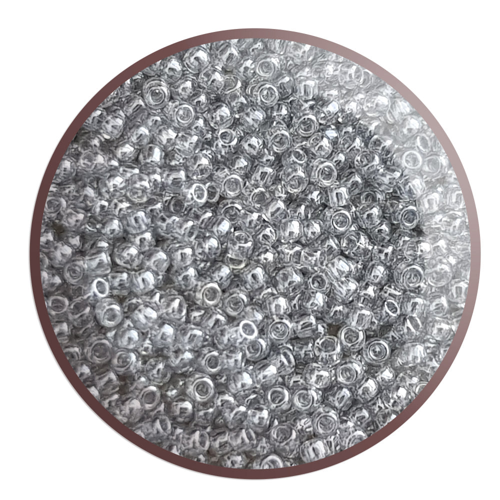 A bowl filled with black diamond transparent luster round Toho seed beads. circle white background.