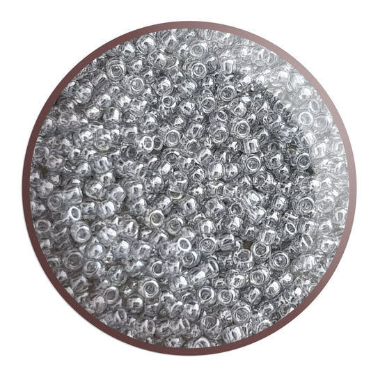 A bowl filled with black diamond transparent luster round Toho seed beads. circle white background.