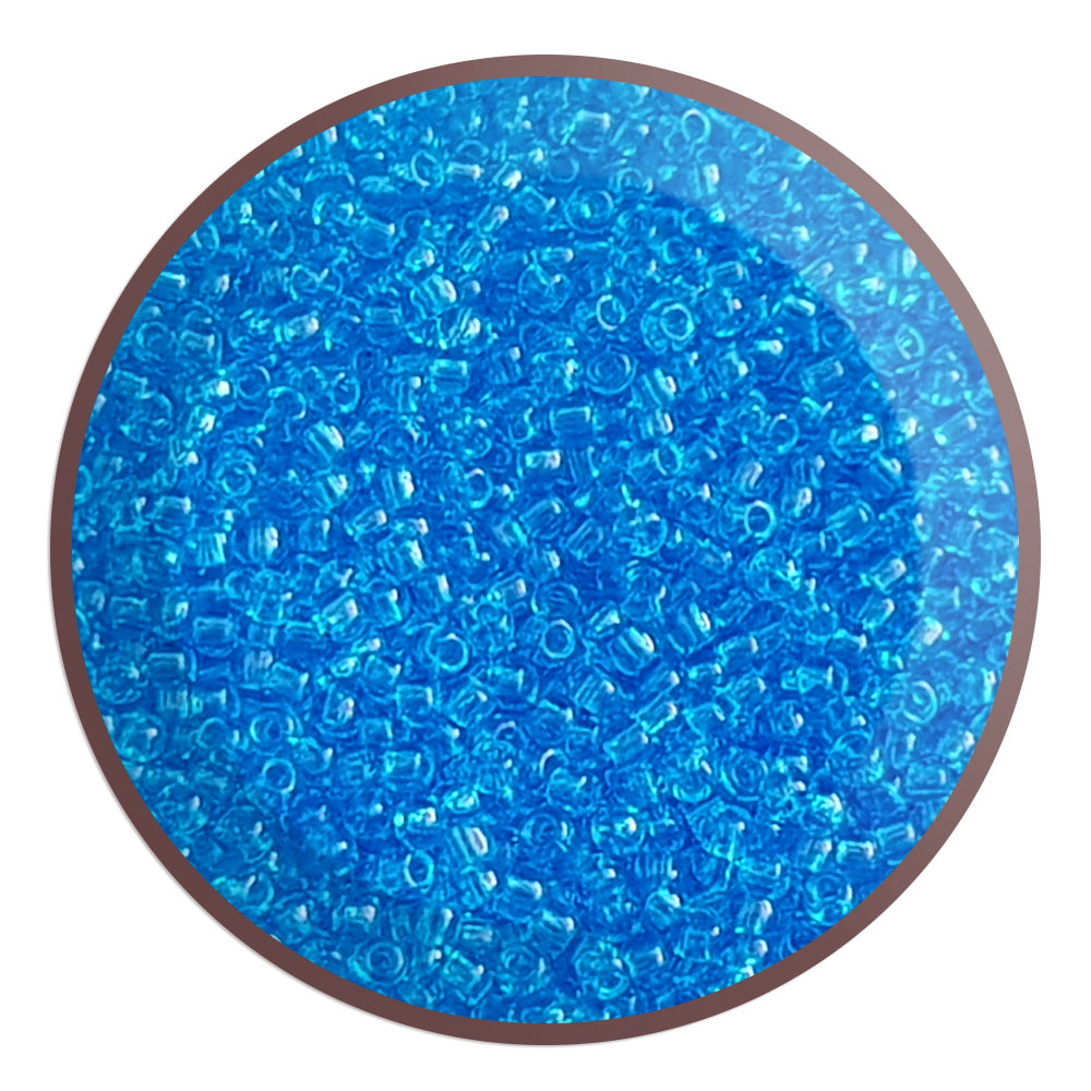 11/0 Toho seed bead in dark aquamarine transparent in a circle white background.