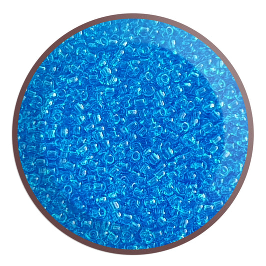 11/0 Toho seed bead in dark aquamarine transparent in a circle white background.