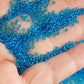 11/0 Toho seed beads in dark aquamarine transparent on a hand.