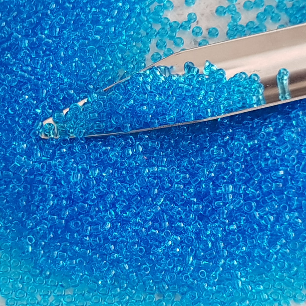 11/0 Toho seed beads in dark aquamarine transparent with a beading scoop.
