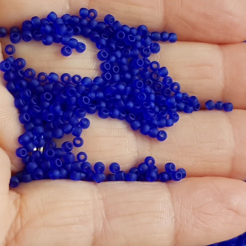 11/0 Toho Seed Beads in Dk. Sapphire frosted transparent on a hand.