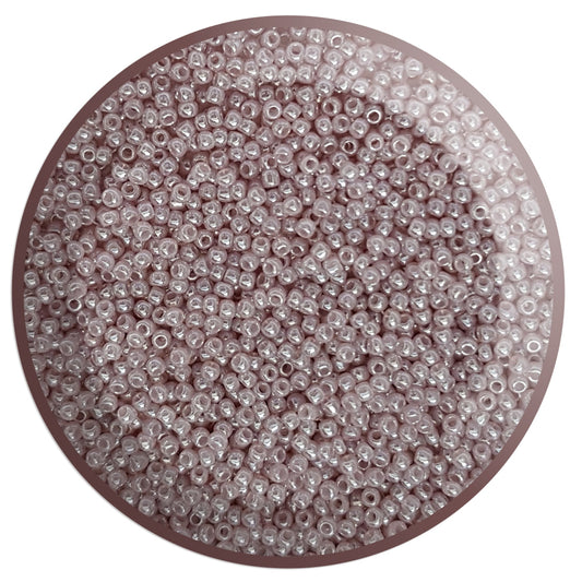 A pile of round Toho seed beads in Grape Mist Ceylon colour 11/0 in a circle with white background,