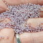 round Toho seed beads in Grape Mist Ceylon colour 11/0 in a a hand.
