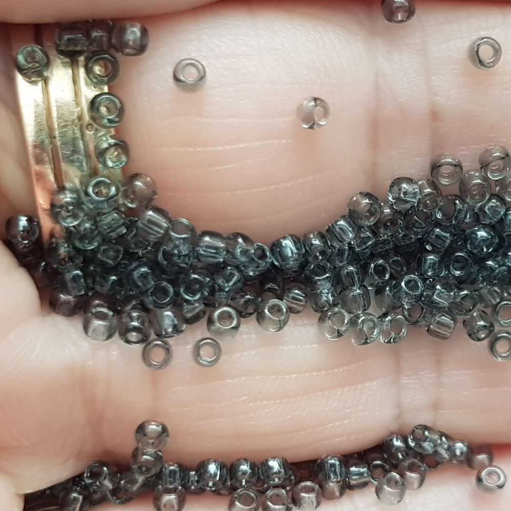 11/0 Toho Seed beads in grey transparent TR-9B close up on a hand.