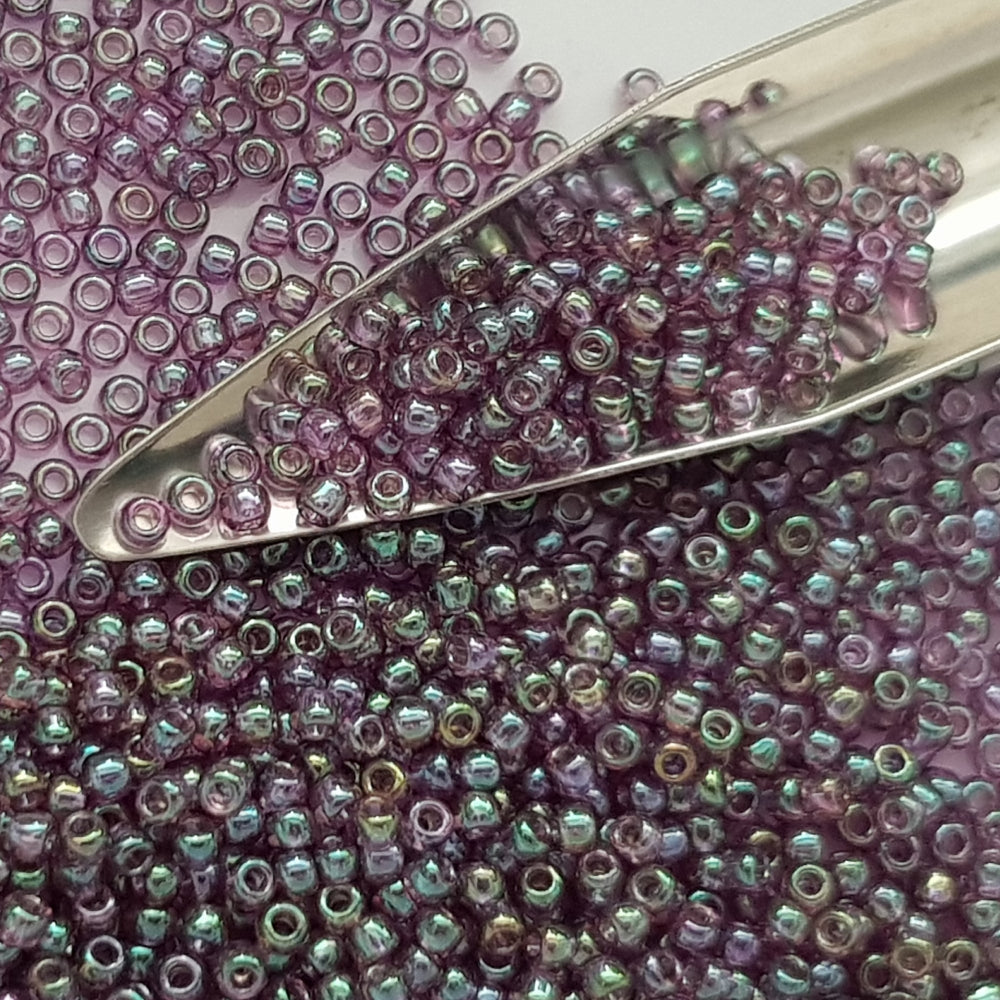 A close-up view of Hydrangea Gold Luster Round Toho Seed Beads 11/0 showing their lustrous finish and multicolored appearance. with a beading scoop.