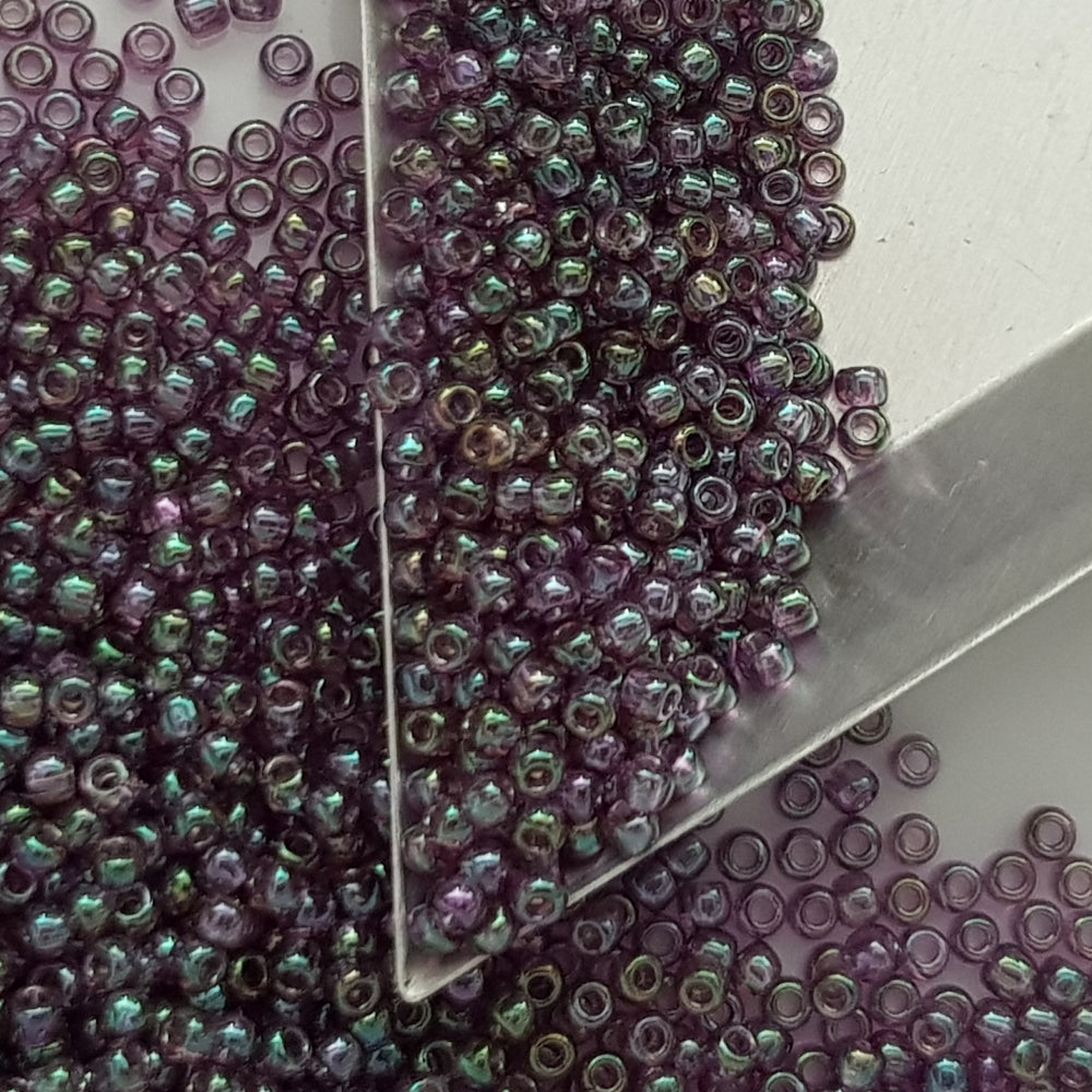 A close-up view of Hydrangea Gold Luster Round Toho Seed Beads 11/0 showing their lustrous finish and multicolored appearance. triangle scoop.
