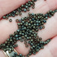 11/0 Toho Seed Beads in Iris Brown Metallic Frosted TR-83F on a hand.