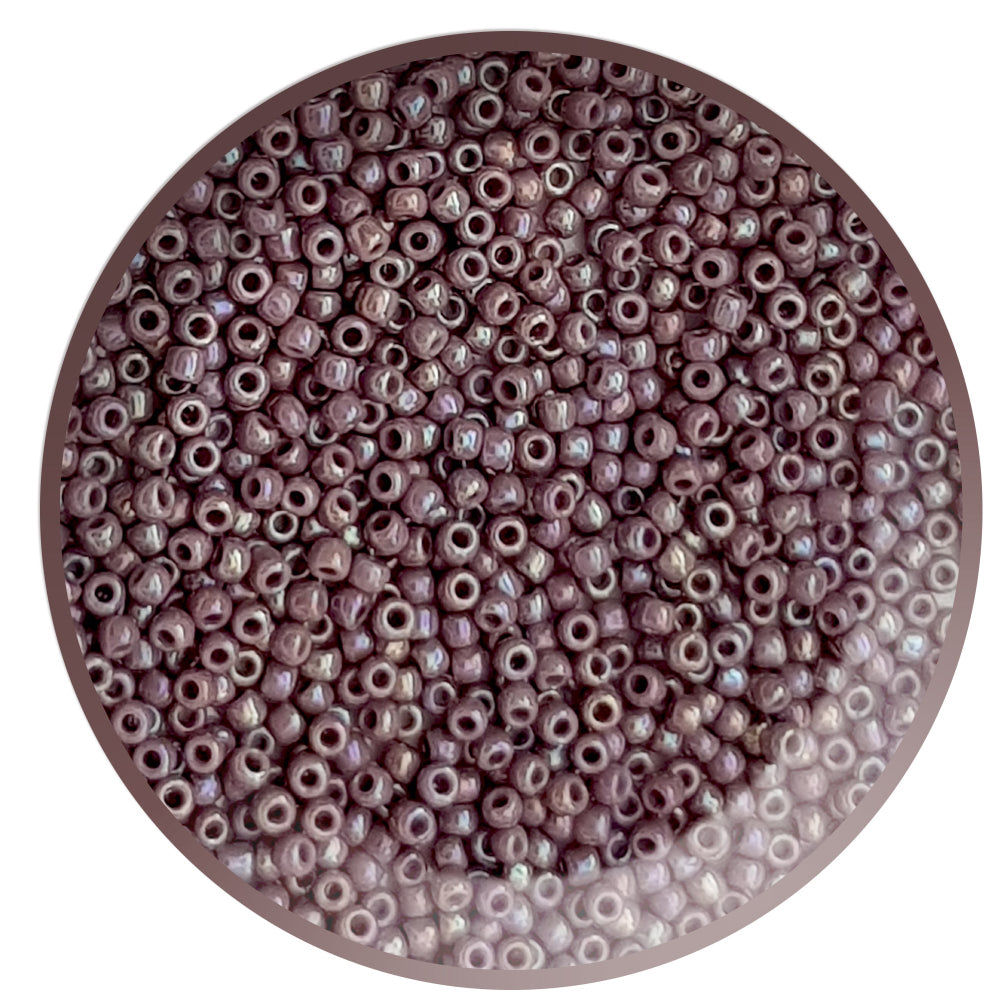 A close-up view of lavender rainbow opaque round Toho seed beads 11/0 in a circle white background.