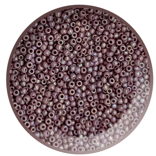 A close-up view of lavender rainbow opaque round Toho seed beads 11/0 in a circle white background.