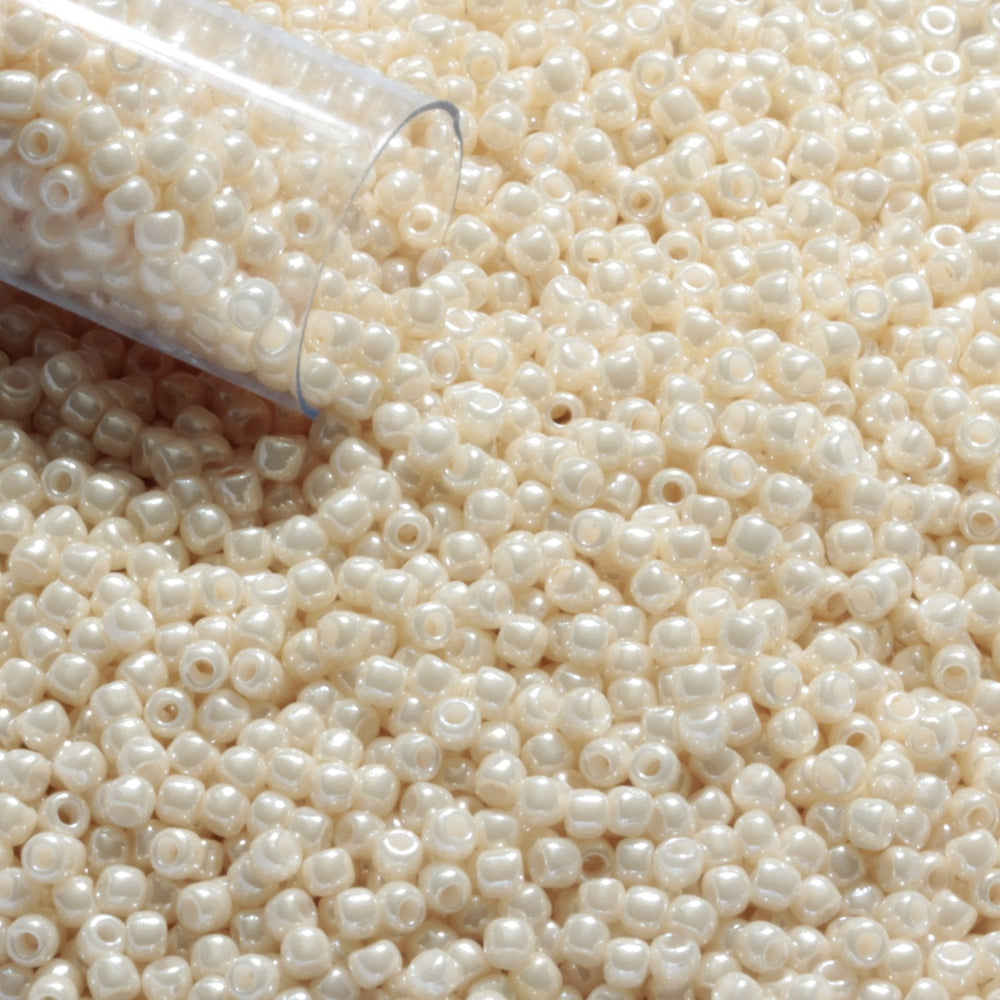 11/0 TR-123 Lt Beige Opaque Luster Round Toho Seed Beads close up with the end of a tube.