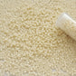 11/0 TR-51 Lt Beige Opaque Round Toho close up with a tip of a tube.