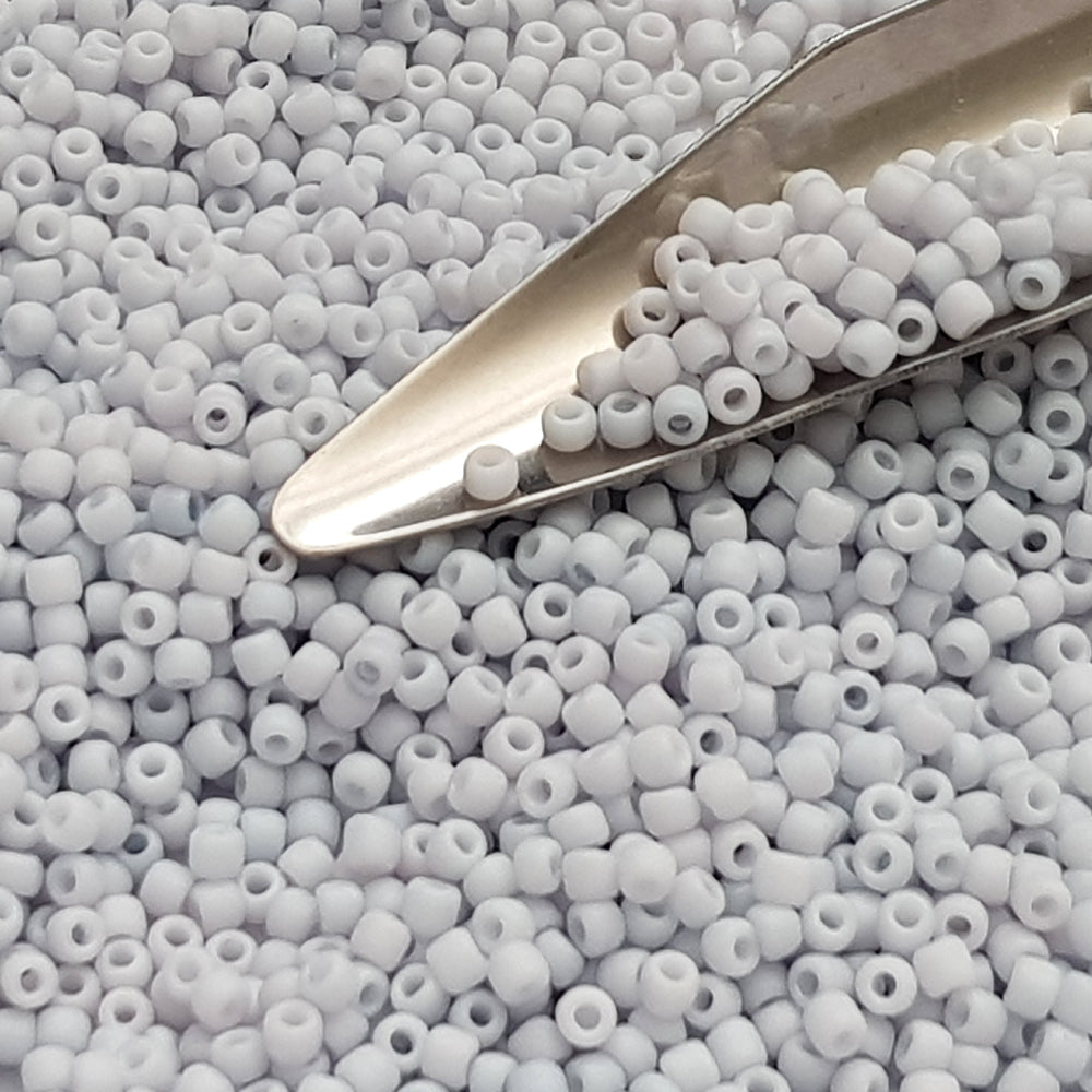 A close-up view of light grey frosted opaque pastel round Toho seed beads. 11/0 Toho Seed Beads, with a beading scoop.
