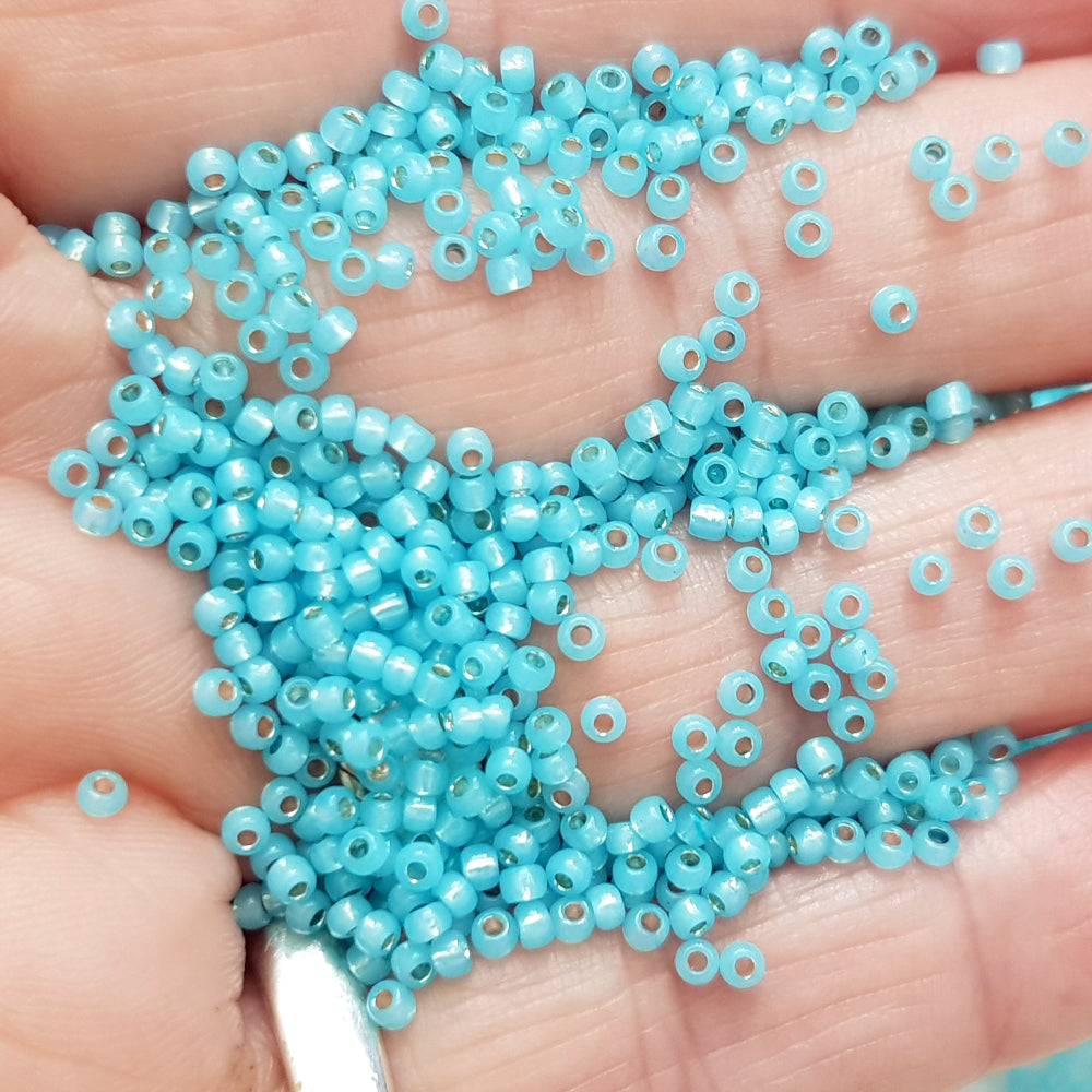 11/0 Toho seed Beads in milky aqua silver-lined on a human hand.
