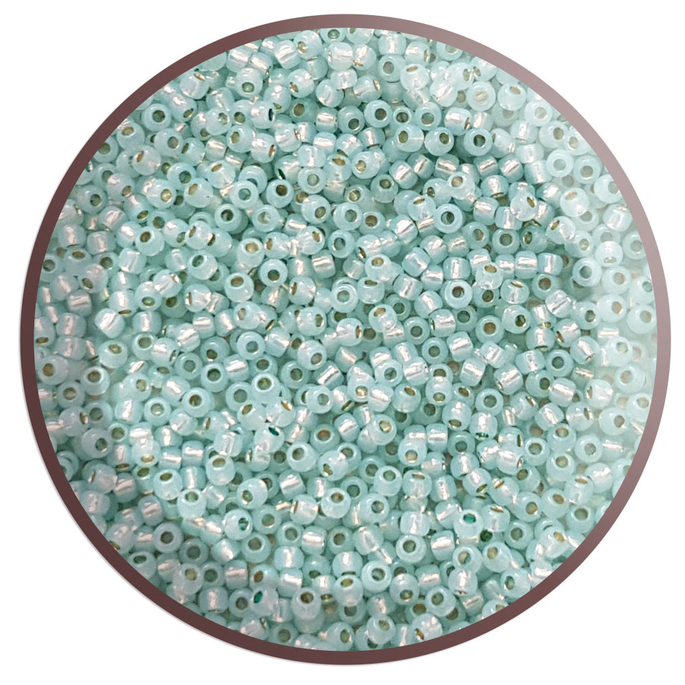 11/0 Toho seed beads in milky Lt Aqua Silver-Lined in a circle with white background.