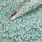 close up of 11/0 milky lt aqua silver-lined Toho seed beads with a beading scoop.