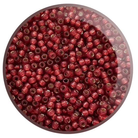11/0 Toho seed beads in milky pomegranate silver-lined in a circle white background.