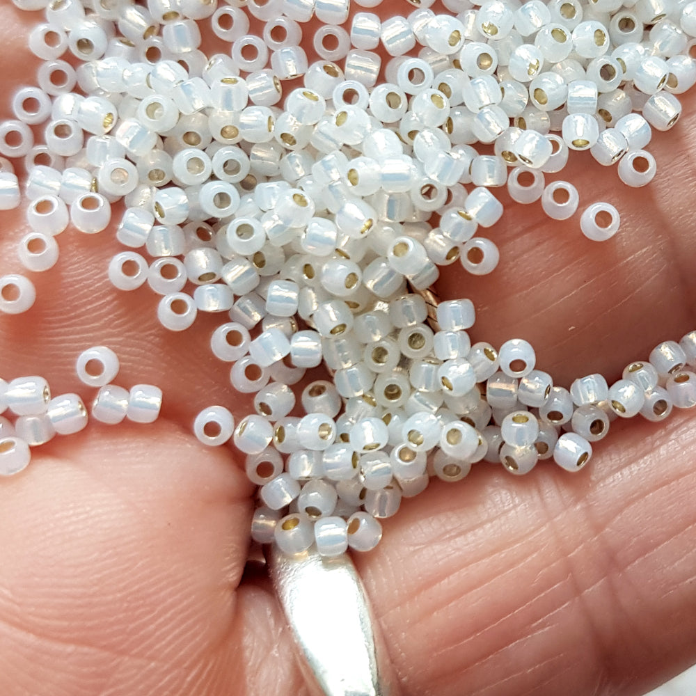 11/0 TR-2100 Milky White Silver Lined Round Toho Seed Beads on a hand