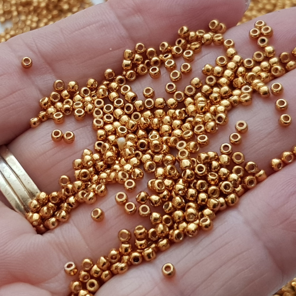11/0 Toho Seed Beads in Old gold Permanent Finish TR-PF591 close up on a hand